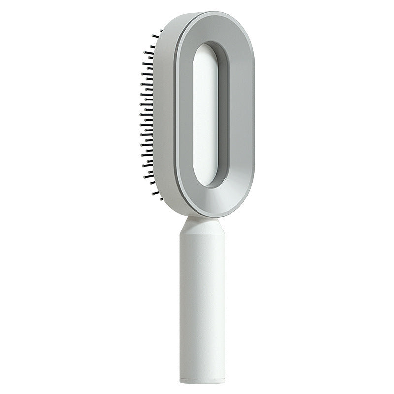Self-cleaning hair brush with white oval head and black pin bristles on a white handle