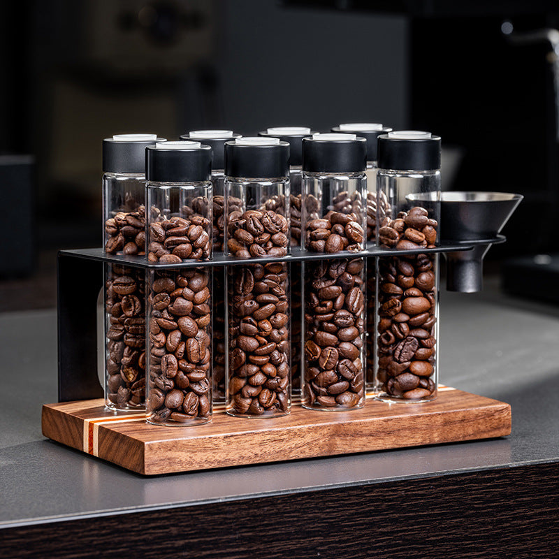 Coffee bean portioning bottle display rack with clear vials and black caps, on wood base.
