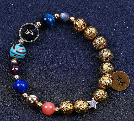 Beaded bracelet with blue and gold beads; round zodiac charm, round pendant, and star detail.