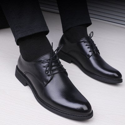 Men's pointed-toe lace-up dress shoes, black leather, worn with dark socks.