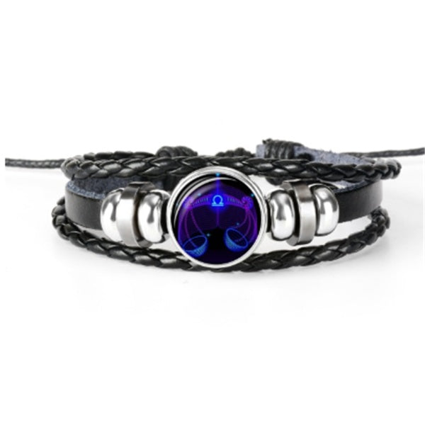 Braided bracelet with a dark round luminous zodiac charm in a chrome-toned ring centerpiece.