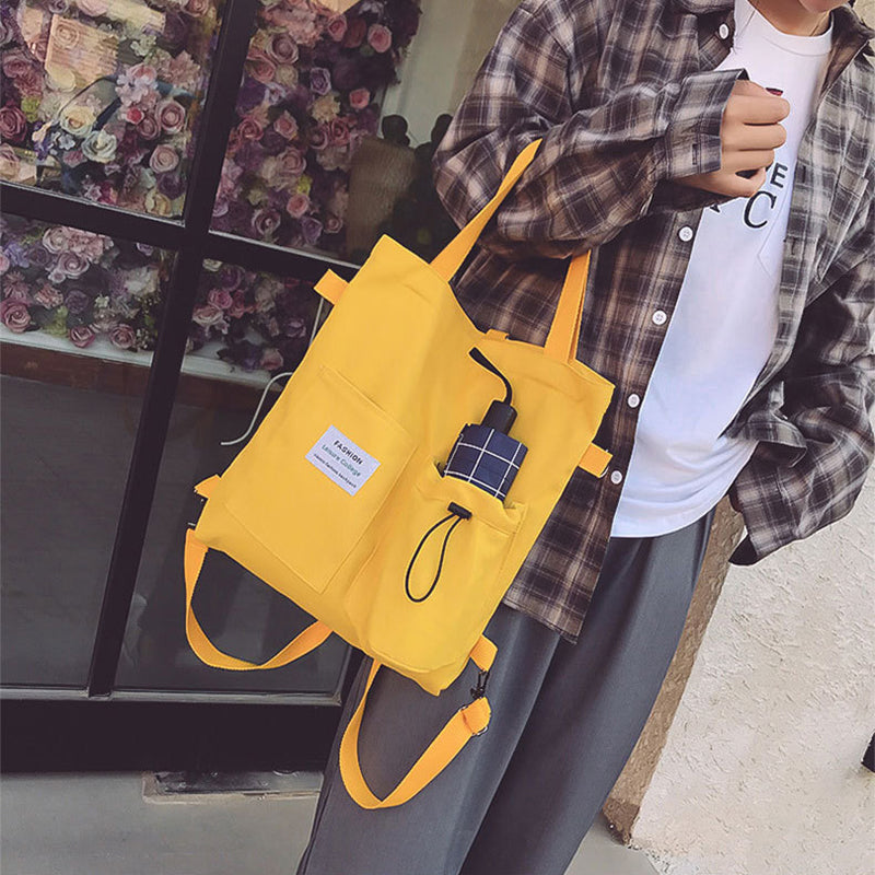 Yellow canvas tote backpack with front pocket and drawstring, plaid patch detail