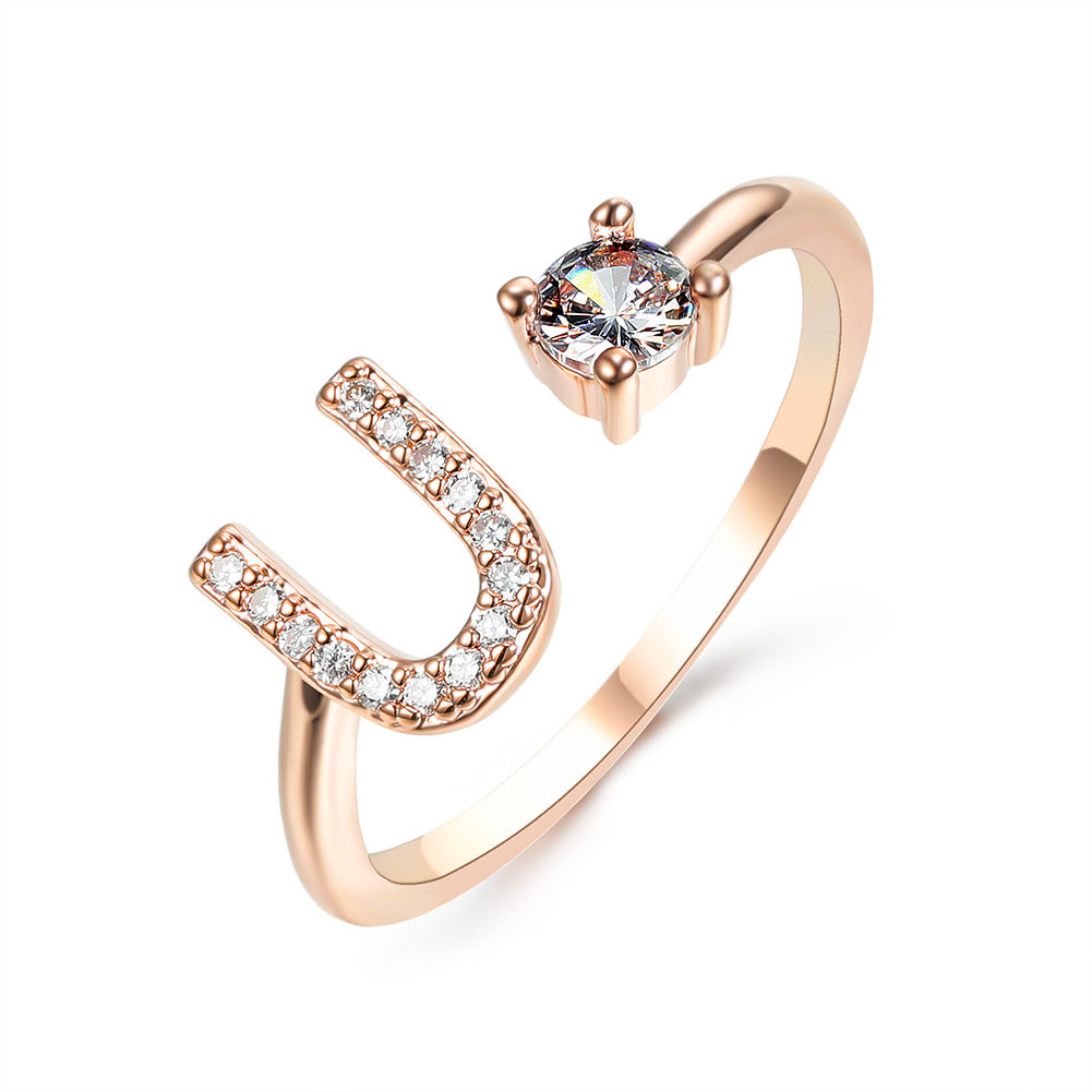 Rose gold adjustable initial ring with U-shaped letter and round center stone.