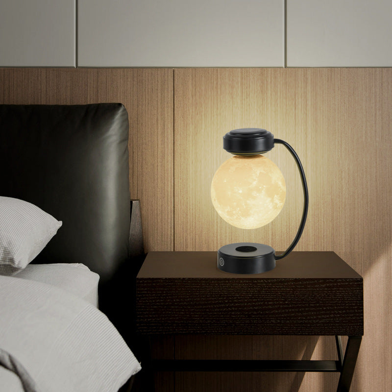 Glowing moon LED night light with black floating globe and arched cable stand