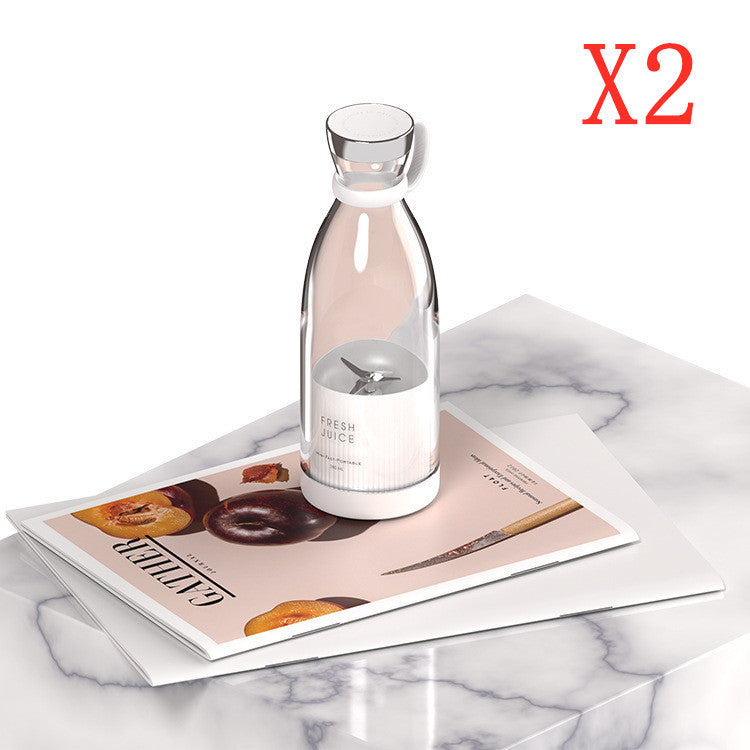 Pink portable electric juicer blender bottle with lid on marble and booklet