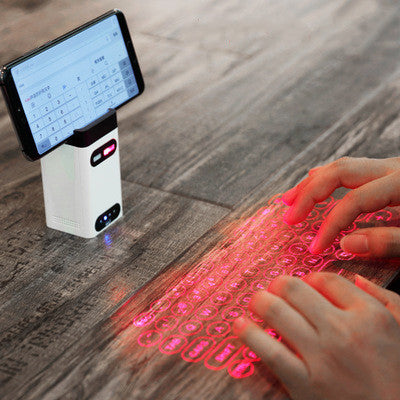 White laser projection keyboard projector casting a red keyboard pattern on a desk