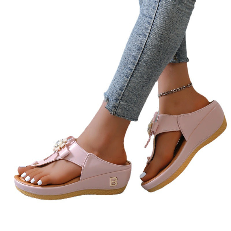 Women’s flower wedge platform flip flops in pink, with buckle strap and perforated footbed