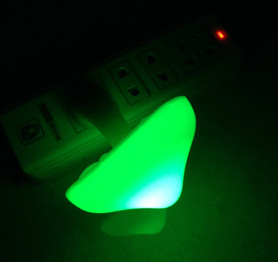 Plug-in mushroom LED night light glowing green from wall outlet