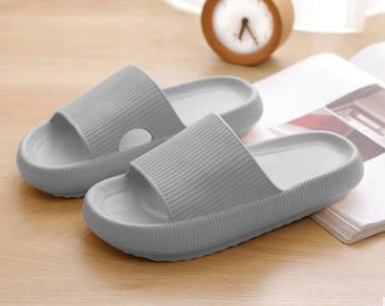 Light gray slide slippers with open toe and textured cross-strap.