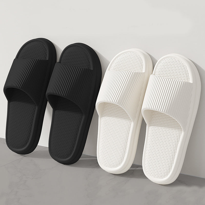 Black and white slip-on home slippers with textured footbeds and ribbed straps
