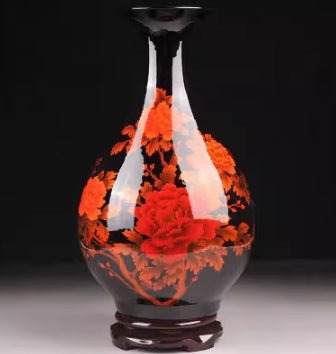 Ceramic vase with orange and red flowers, slender neck and dark pedestal base