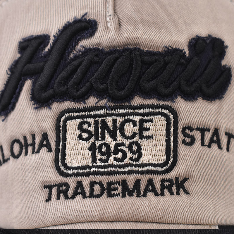 Beige baseball cap fabric close-up with embroidered “Since 1959” patch detail