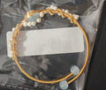 Gold pearl cuff bracelet with blue stones and white pearls in clear plastic bag