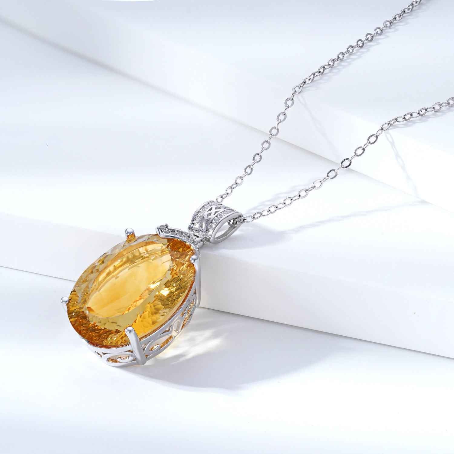 Silver necklace with large oval yellow gemstone pendant in ornate frame