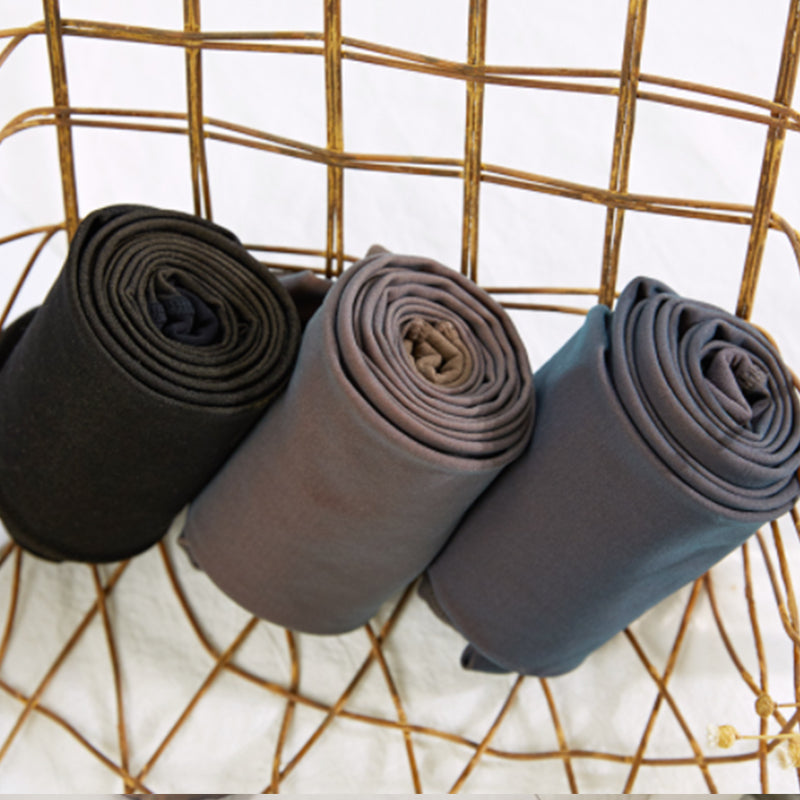 Fleece-lined pantyhose rolls in black, taupe, and blue on a grid stand