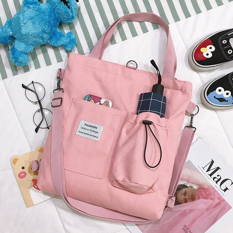 Pink canvas tote bag with front pocket and drawstring, plaid patch detail