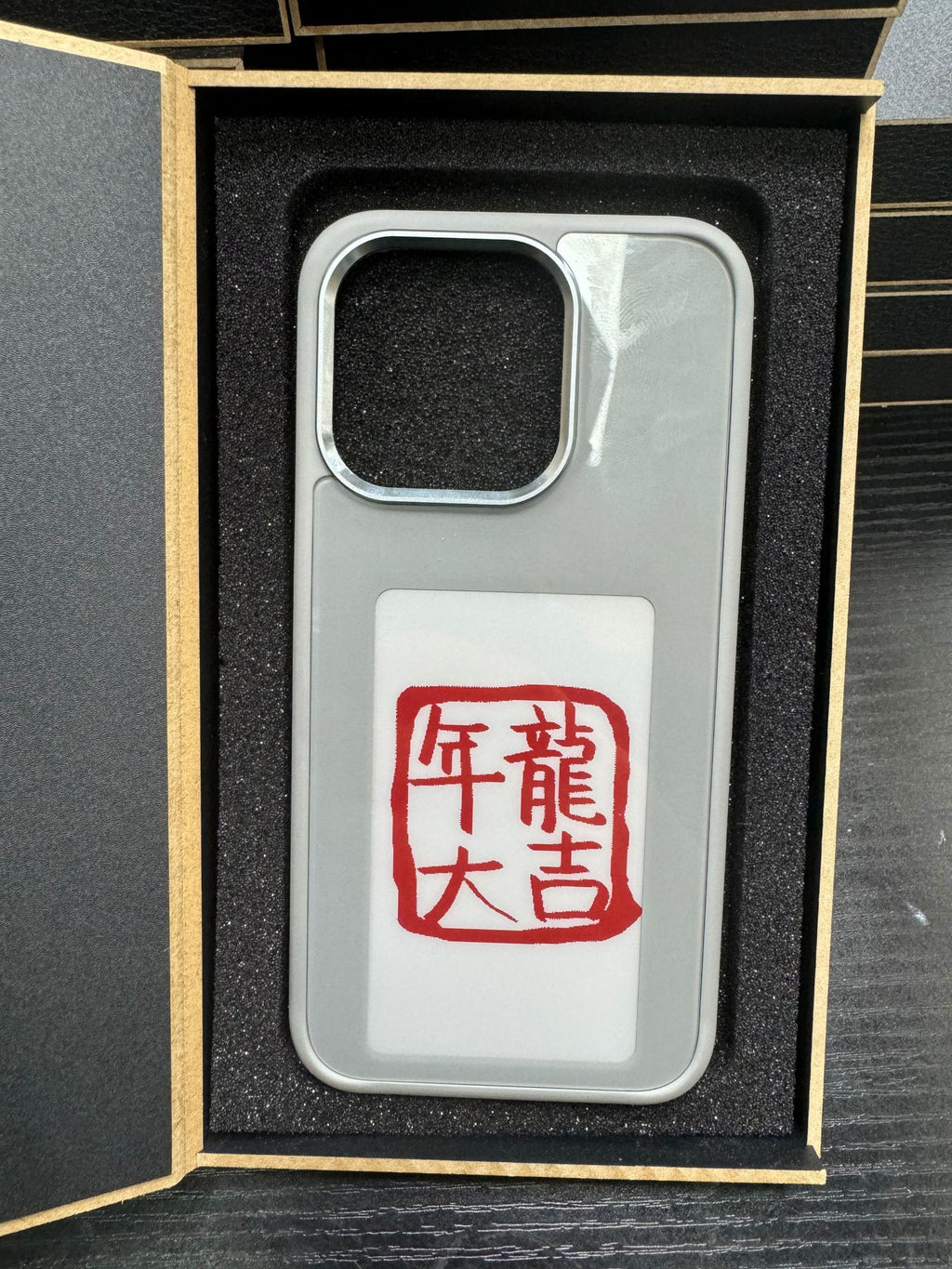 Gray phone case with camera cutout and red character stamp display decal