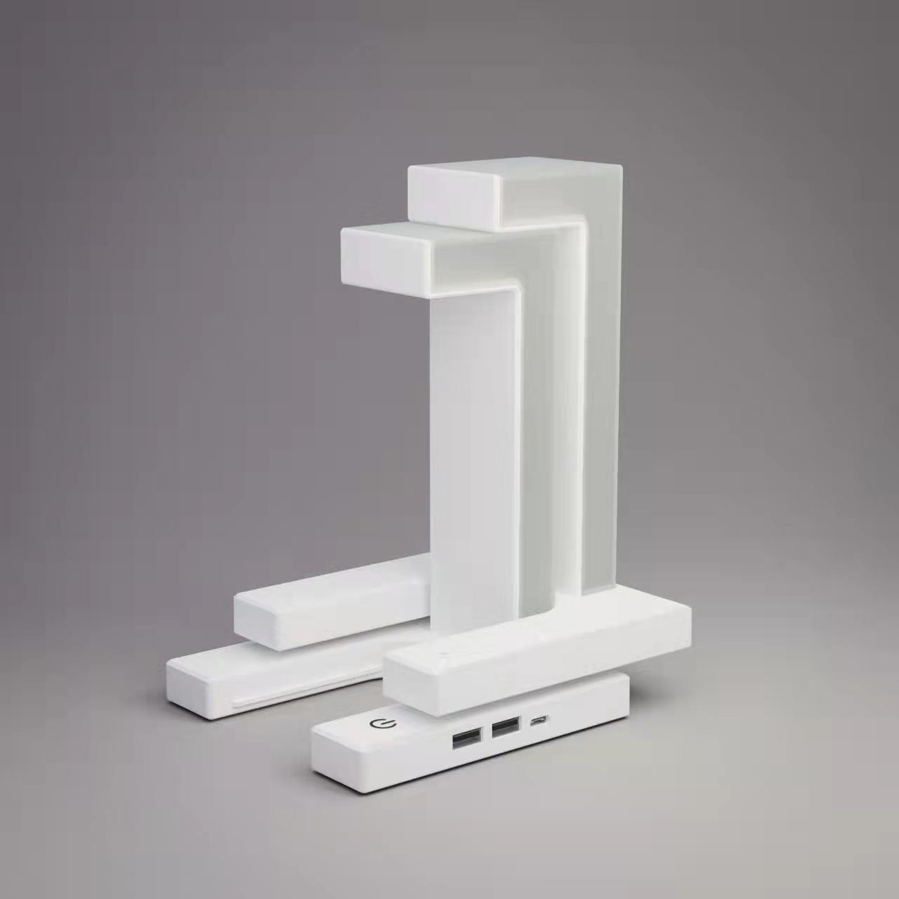 White wireless charging table lamp with sculpted frame and phone charging base with ports