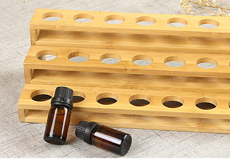 Wood essential oil rack with two tiers of round bottle holes and a couple of vials