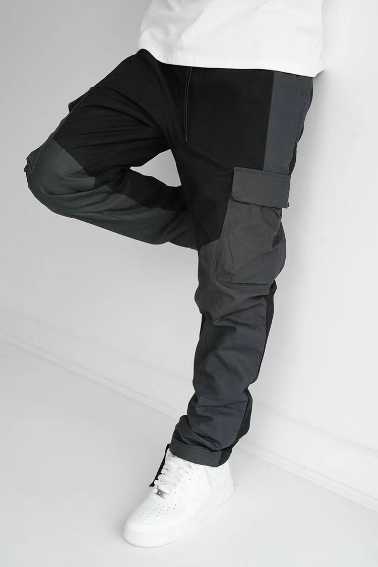 Black cargo trousers with stitched pocket panels, relaxed fit, cuffed ankle hem