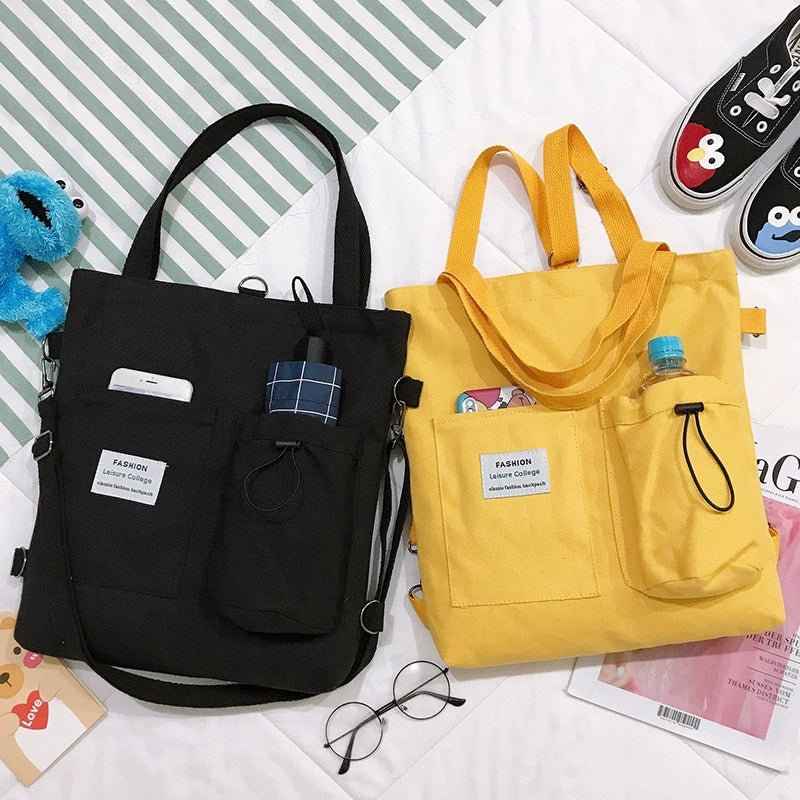 Canvas tote bags in black and yellow, each with front pocket, drawstring, and plaid patch