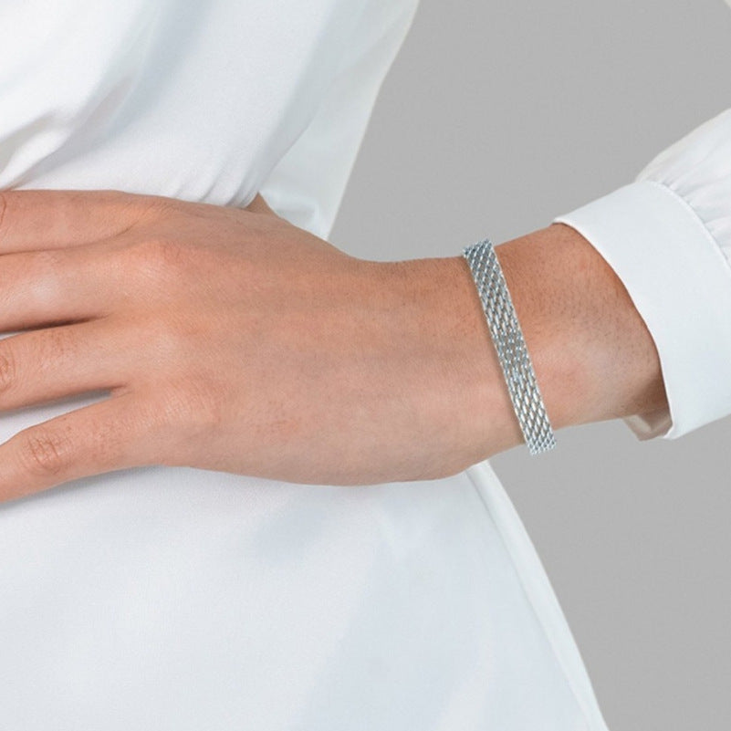 Silver chain bracelet on wrist over white shirt cuff, mesh link style