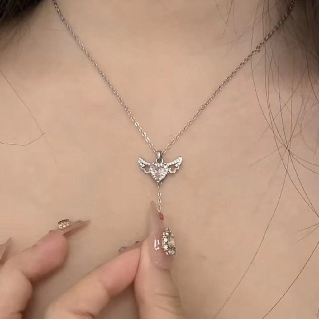 Angel wing heart necklace with crystal centerpiece and dangling charm on a silver-toned chain