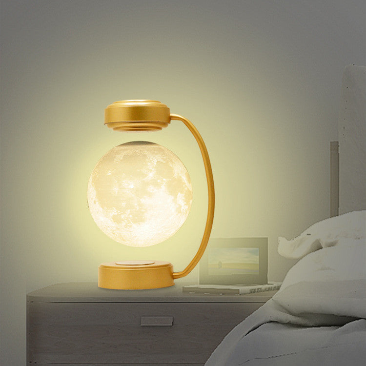 Gold moon LED night light with warm glowing floating globe and arched charging base
