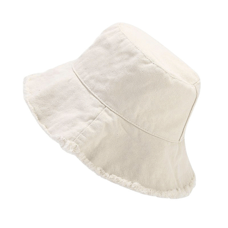 White sun hat with wide brim, stitched panels, and frayed trim.