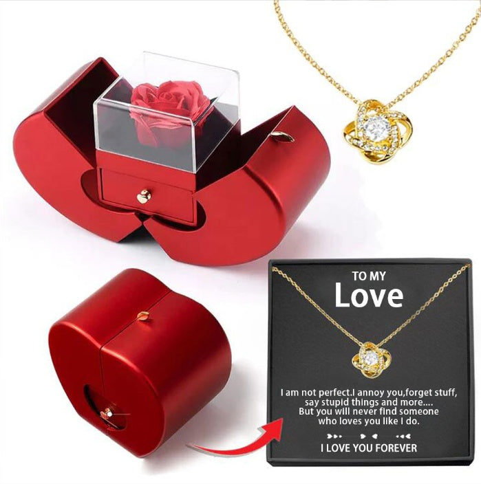 Red jewelry box with clear cover holding a red rose; gold heart pendant and gift card shown