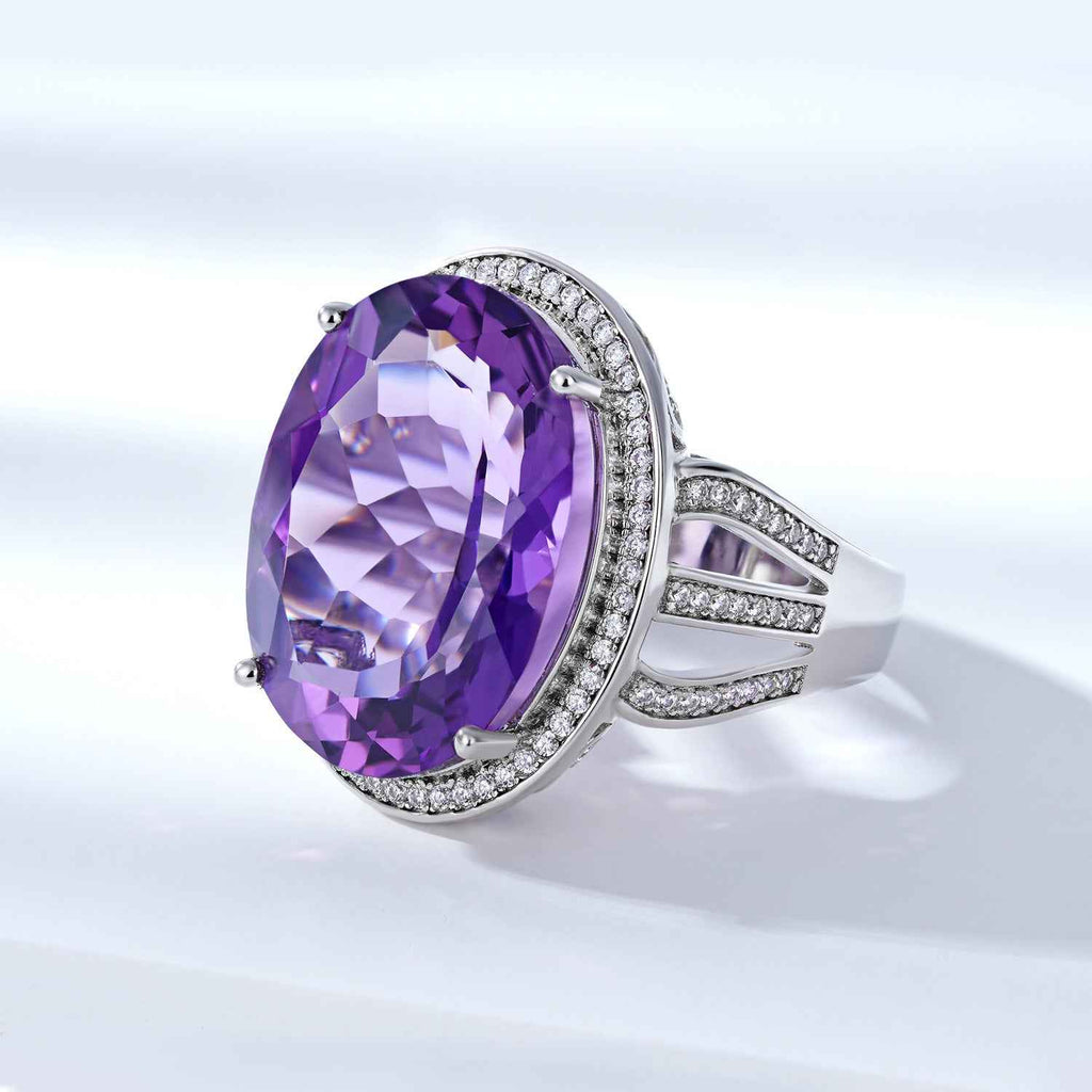 Silver amethyst ring with oval purple gemstone haloed by small clear stones, wide band